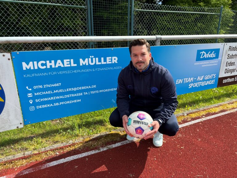 Michael Müller kniet vor der neuen Bandenwerbung für seine DEBEKA Bezirksleitung.